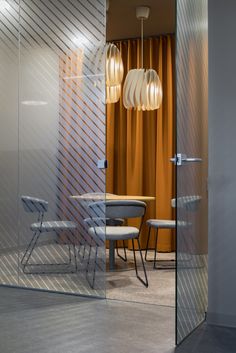 an open glass door leading to a dining room with chairs and a table in it