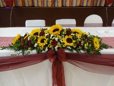 the table is set with sunflowers and other flowers on it, along with red ribbon