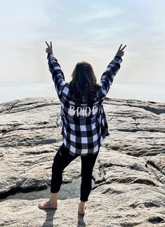 a woman standing on top of a rock covered ground with her arms outstretched in the air