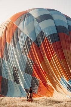 a woman is standing in front of a large hot air balloon that has been painted orange and blue