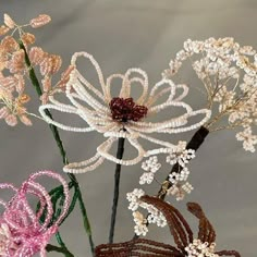 three flowers with beaded stems in vases