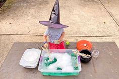 a little boy in a witches hat playing with foam