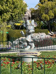 a statue of mickey mouse in the middle of a flower garden