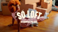 a woman laying on the floor next to boxes with a laptop in her lap and an orange afro wig