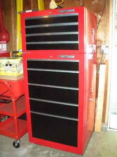 a red and black toolbox sitting on top of a workbench in a garage