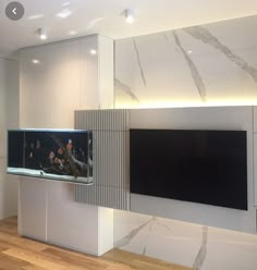 a fish tank sitting on top of a white cabinet next to a wall mounted tv