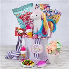 a unicorn toy sitting in a bucket filled with candy and candies next to other items