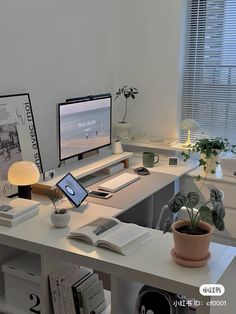 a desk with a computer, laptop and books on it in front of a window