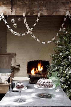 a table topped with cake next to a fire place covered in christmas lights and decorations