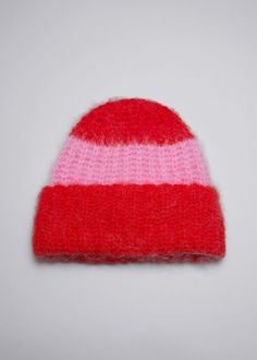 a red and pink knitted hat on a white surface