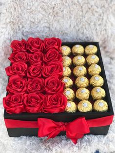 a box filled with roses and chocolates on top of a white blanket next to a red bow