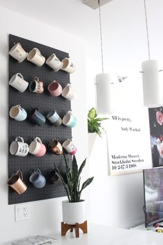 a pegboard with cups and mugs on it in front of a white wall