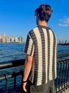 a man standing next to the water looking at the city