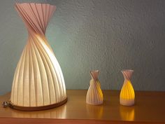 three vases sitting on a table next to each other in front of a wall