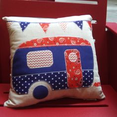 a pillow with an rv design on it sitting on a red chair in front of a window