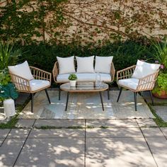 two chairs and a coffee table in front of a wall with plants on the side