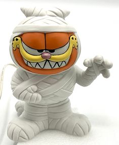 a white and orange figurine sitting on top of a white floor next to a cord