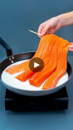 someone cooking salmon in a frying pan