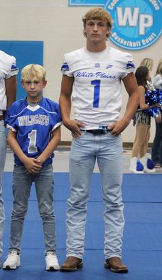 two young boys and an older man standing in front of a blue carpeted floor