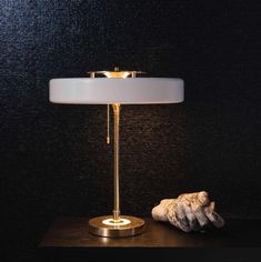 a table lamp sitting on top of a wooden table next to a sea urn