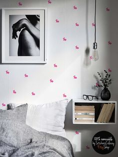 a bed room with a neatly made bed and pink butterflies on the wall above it