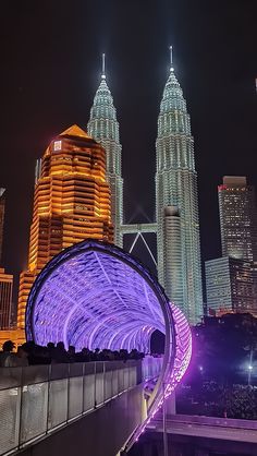 the city skyline is lit up at night with tall buildings in the backgroud