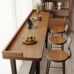 a wooden table with four chairs and a bowl of fruit on it next to a book shelf