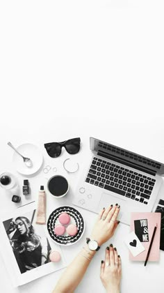 a woman sitting at a desk with her laptop and other items on the table next to her