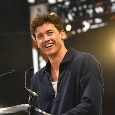 a smiling man standing at a podium in front of a microphone