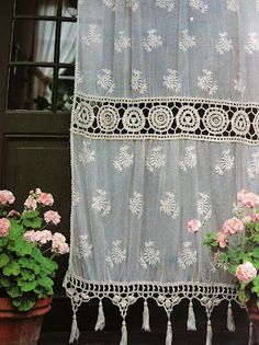 two potted plants sitting next to each other in front of a window with sheer curtains