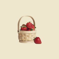 two strawberries in a basket on a pink background, with one strawberry still attached to the basket