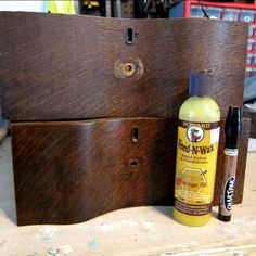 a bottle of wax next to a wooden box with some glue on it and a pen