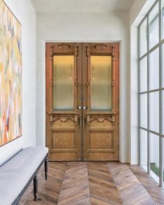 an entryway with two wooden doors and a bench