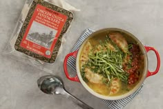 a red pot filled with food next to a bag of chicken broth