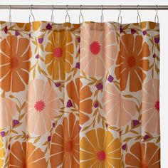 an orange and pink flowered curtain hanging from a metal rod