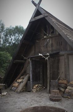 an old wooden building with a cross on it's roof and fire pit in the foreground