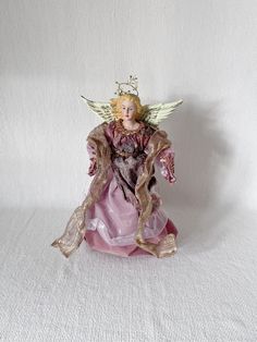 an angel figurine sitting on top of a white cloth covered floor next to a wall