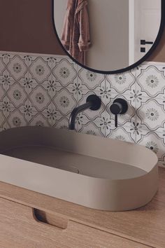 a bathroom sink sitting under a round mirror