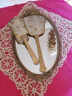 three antique gold plated serving utensils on a pink tablecloth with lace doily