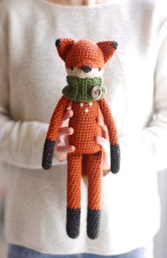 a woman holding a knitted fox doll in her hands