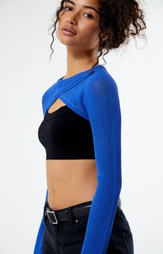 a woman wearing a blue crop top and black pants with her hands on her hips