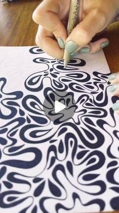 a woman with green nails is using a pencil to draw an intricate design on a piece of paper