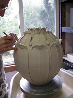 a woman is working on a vase in the process of making it into a sculpture