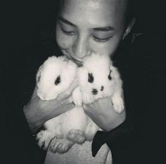 a woman holding two small white rabbits in her hands