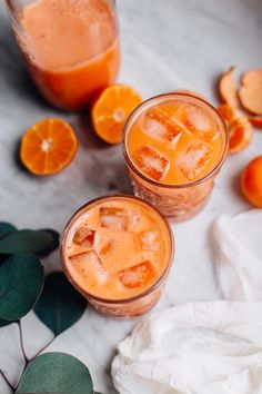 two glasses filled with orange juice next to sliced oranges