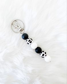 a keychain with black and white balls on it sitting on a furry surface