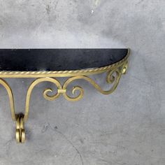 a metal shelf with a black marble top and gold trimmings on the edge