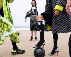 a group of people standing on top of a beach next to each other with soccer balls