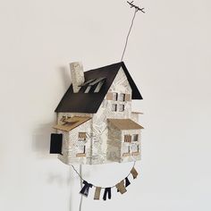 a paper house hanging from the side of a wall