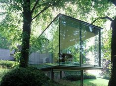 the glass house is surrounded by trees and bushes